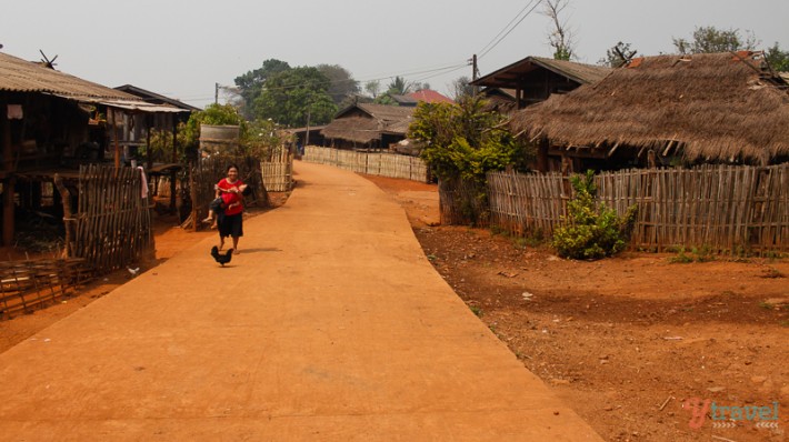 woman walking on dirt road through Akha hill tribe village