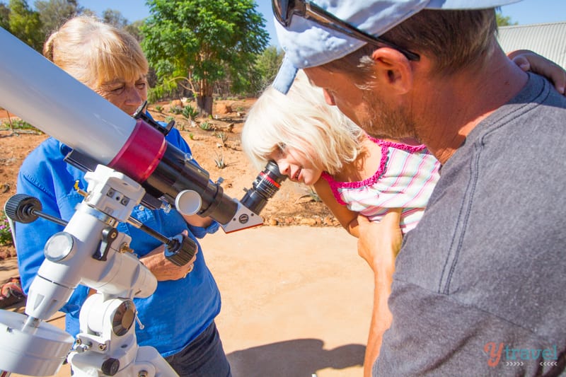 girl looking through a telescope