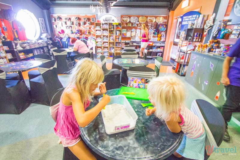 A little girl sitting at a table in front of a store