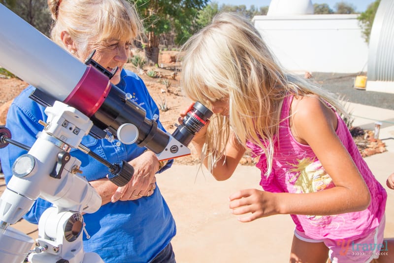 girl looking through a telescope