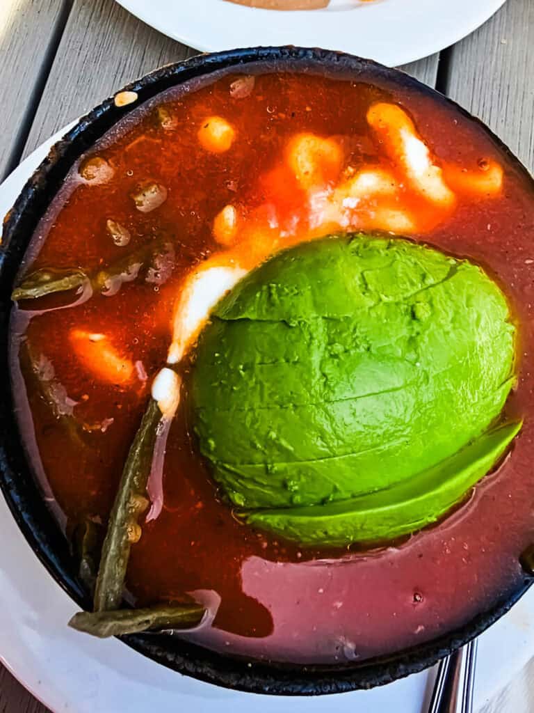 bowl of tomato soup with avocado on top