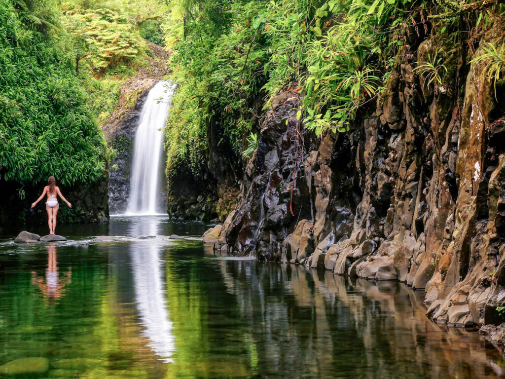 woman standing on rock looking at Wainibau Waterfall in fijii