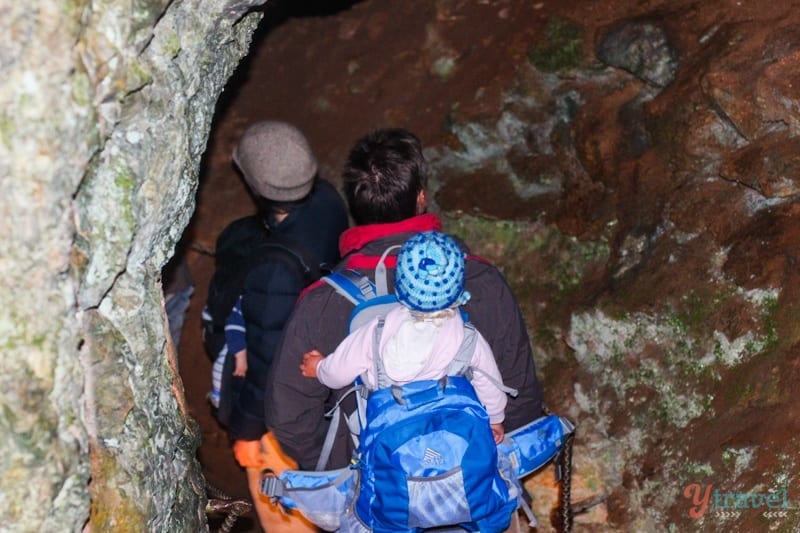 man with child on back walking down into Yarrangobilly Caves, 