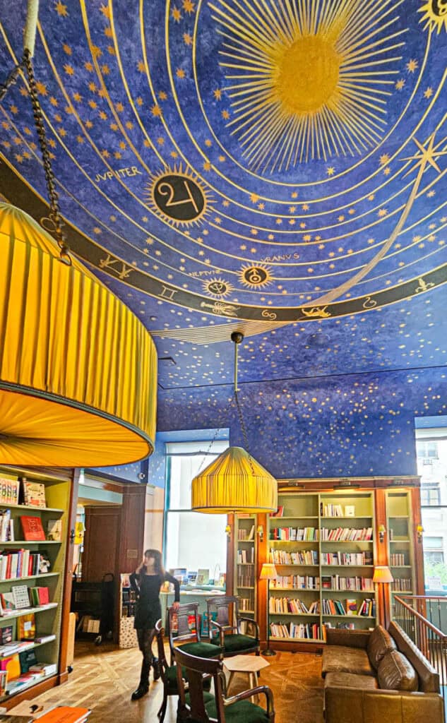 girl standing in albertine bookstore with celestial painting on ceiling