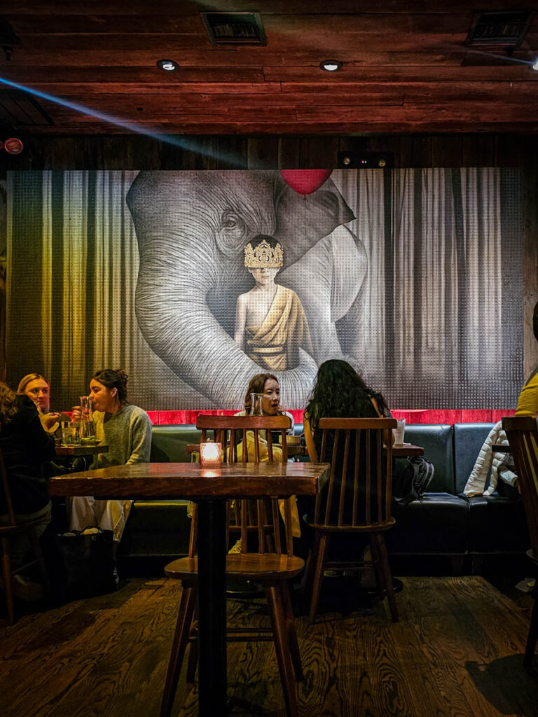 people in obao restaurant with mural of monk and elephant on wall