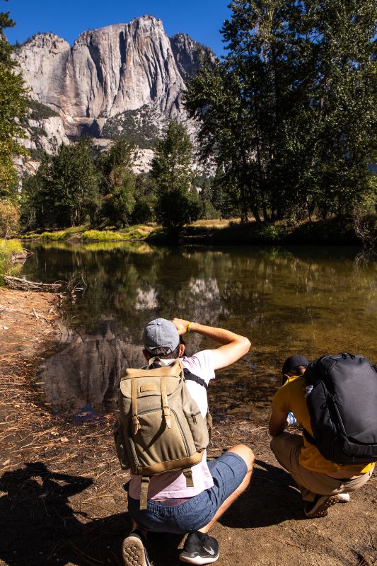 man taking photos of merced river and mountains in yosemite