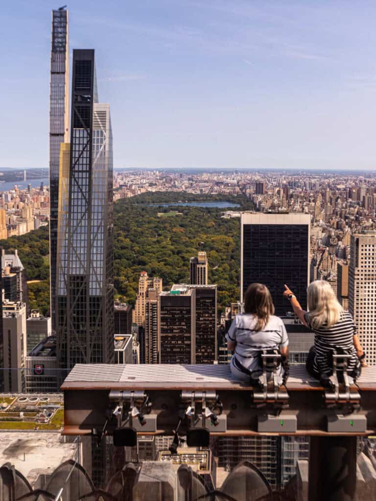 two women on beam looking out over central park view from top of the rock