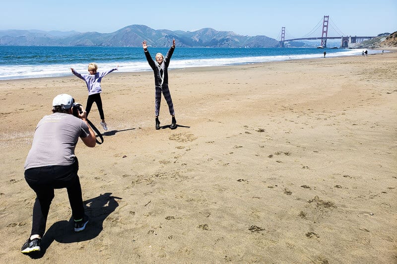 man taking photo of girls jumping on beach