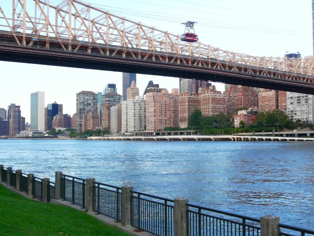 roosevelt tram going over the river beside a bridge in new york