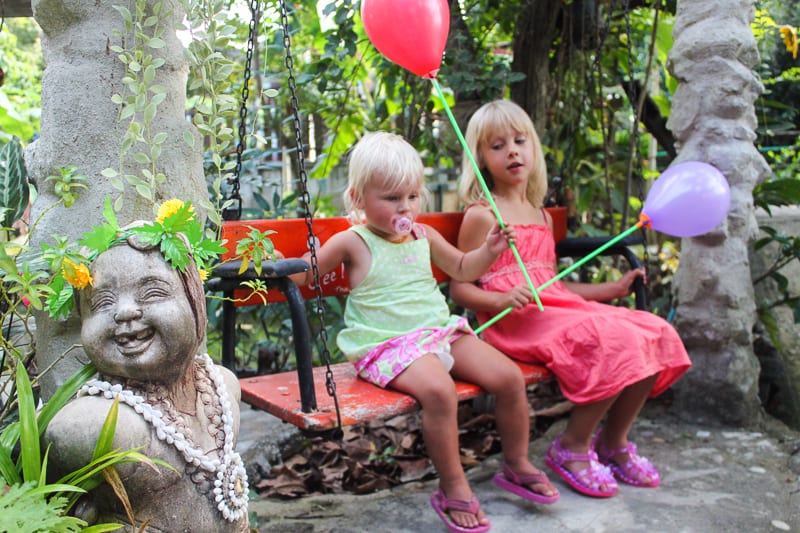 girls holding balloons and sitting on a bench