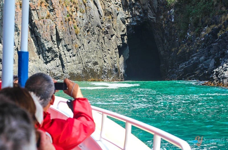 a boat on water next to a cliff