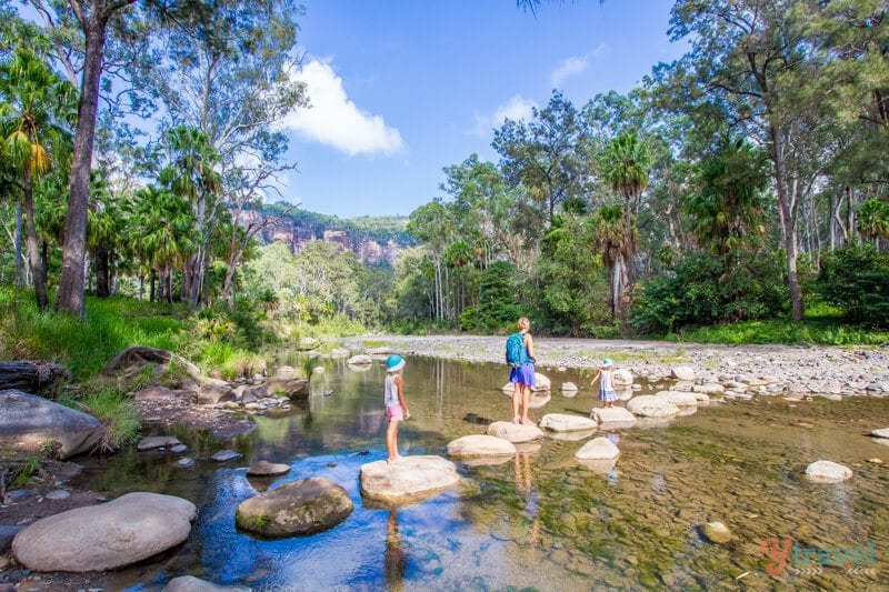 people walking on rocks over a river