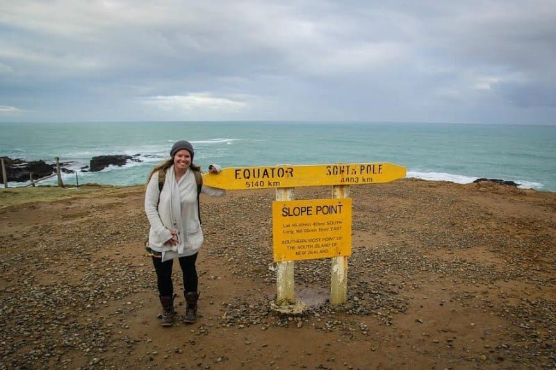 girl standing next to sign at The Catlins - New Zealand