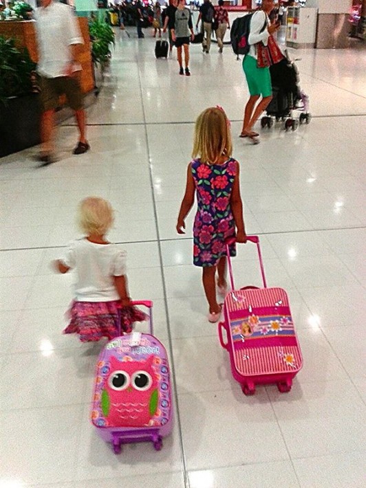 kids rolling suitcase through airport