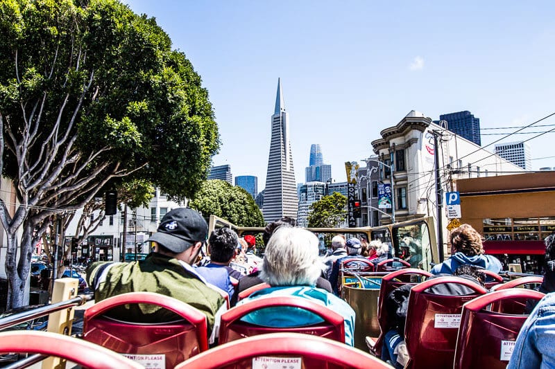 people on open roof bus looking at san francisco view