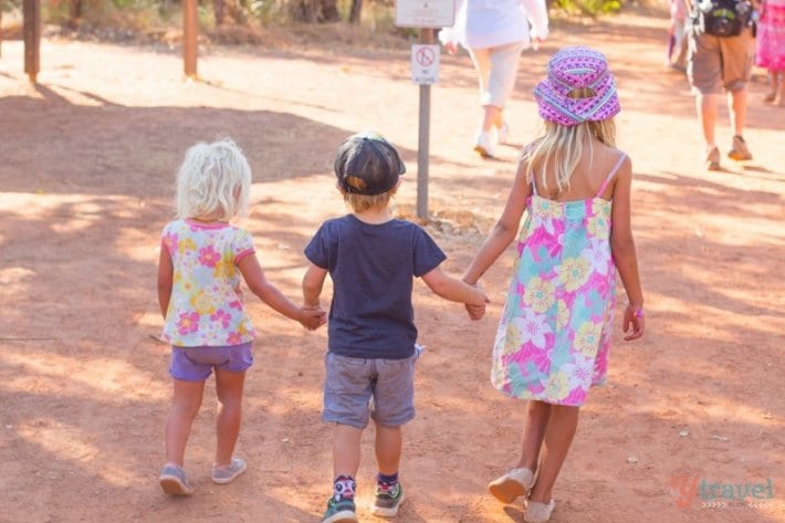 three kids holding hands walking