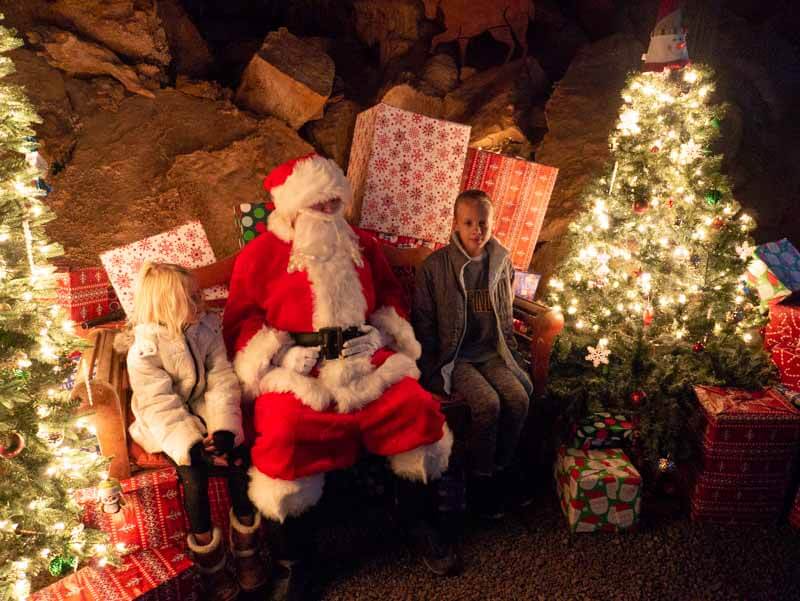 girls sitting next to santa in cavern