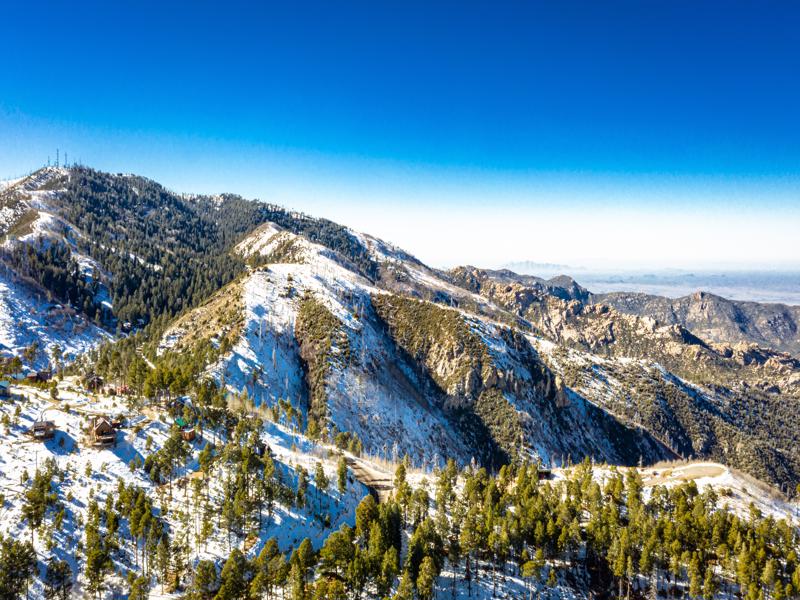 An aerial image of the summit of Mt. Lemmon outside of Tucson, Arizona covered in snow with a vibrant blue sky.