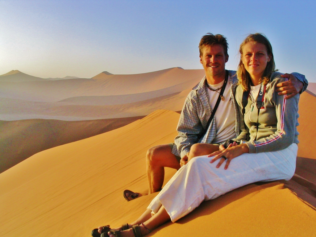 people sitting on top of a sand dune