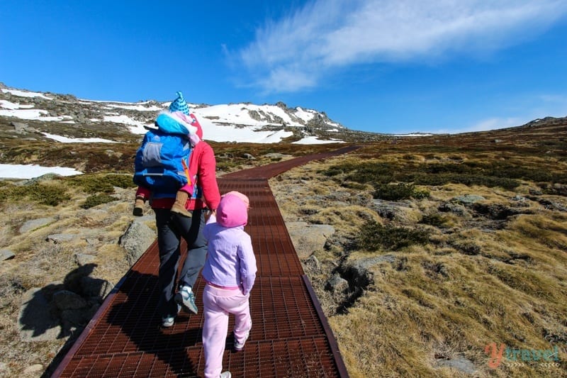 man and children walking up snowy path in mt kosciusko