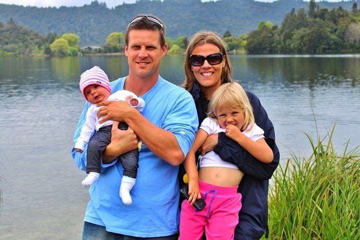 family of four posing beside lake