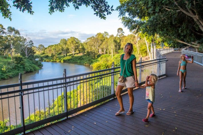 woman walking along a riverfront path holding girls hand