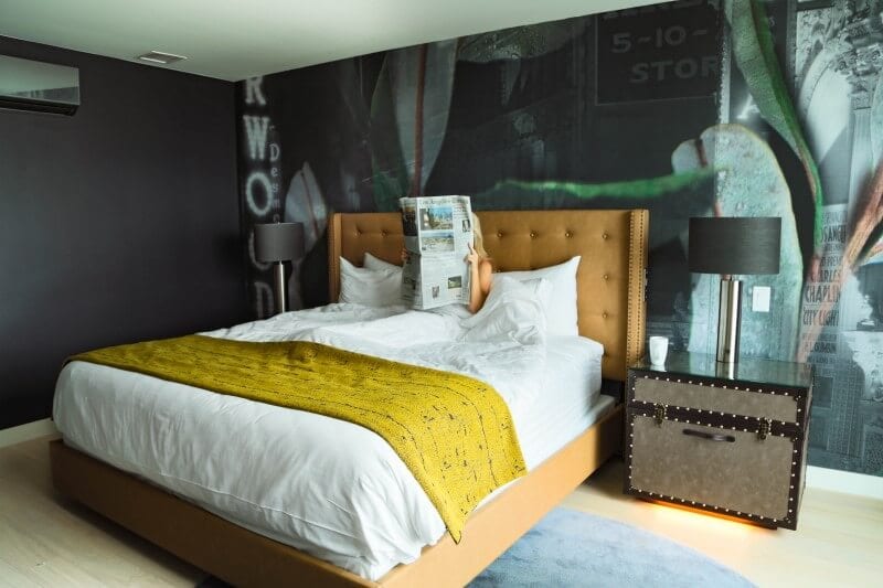 woman reading paper in hotel bed