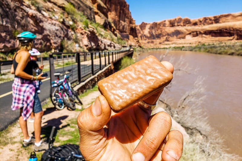 man holding tim tam beside colorado river