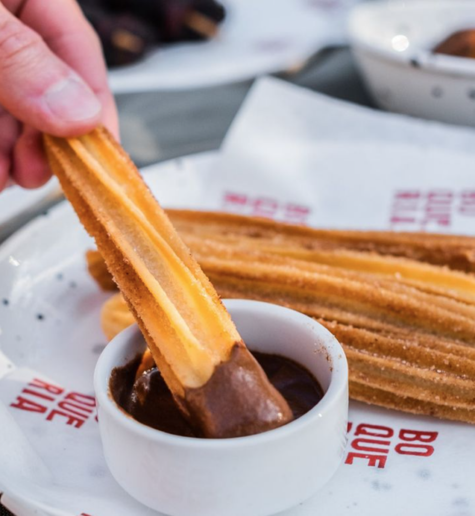 person dipping churros into chocolate sauce