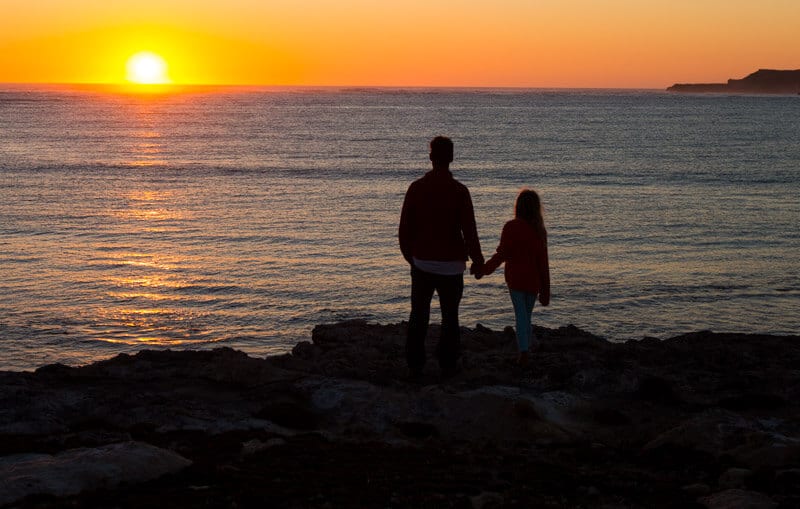 people standing on a cliff holding hands