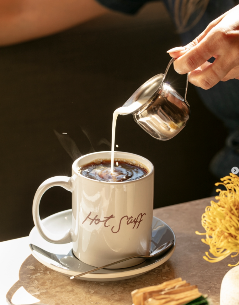 person pouring milk into coffee