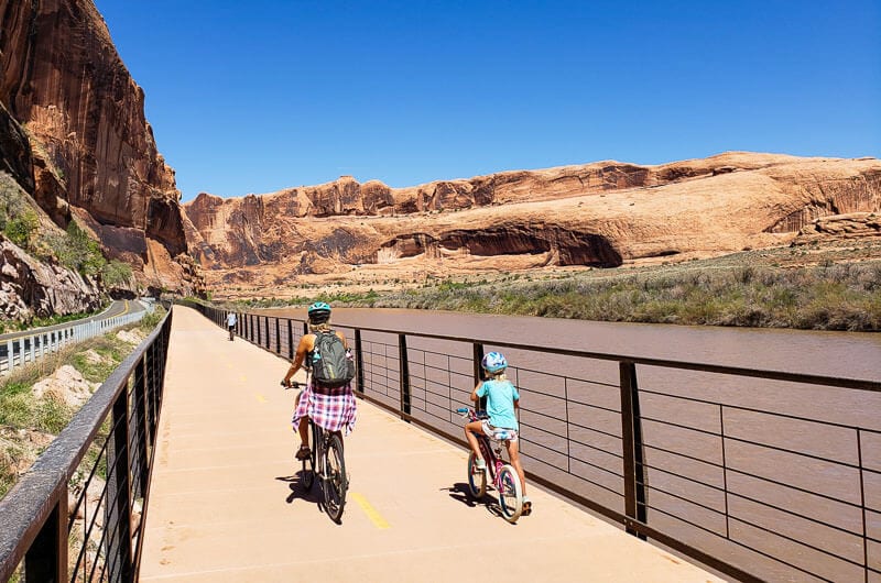 family bike riding beside Colorado river Moab Utah