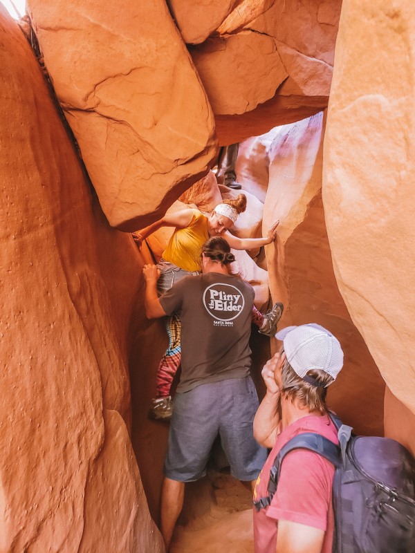 people climbing up narrow spooky canyon