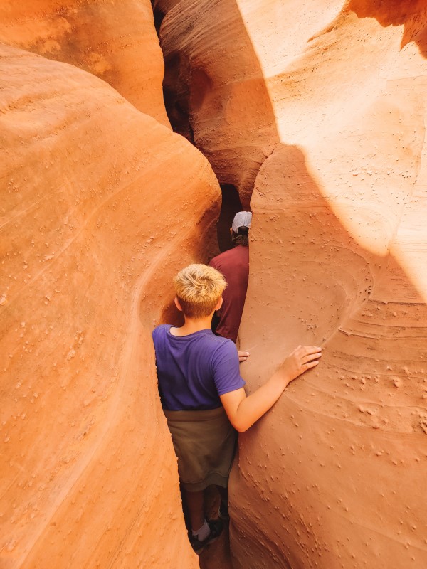 kids  walking sideways through narrow spooky slot canyon