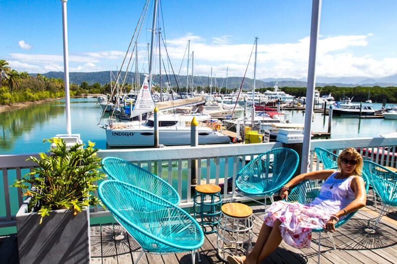 woman sitting in chair at port douglas marina with boats in background