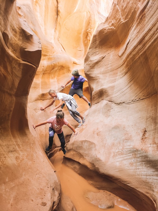 kids climbing on walls of slot canyon