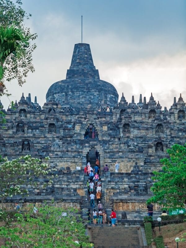 people walking up steep stairs of temple