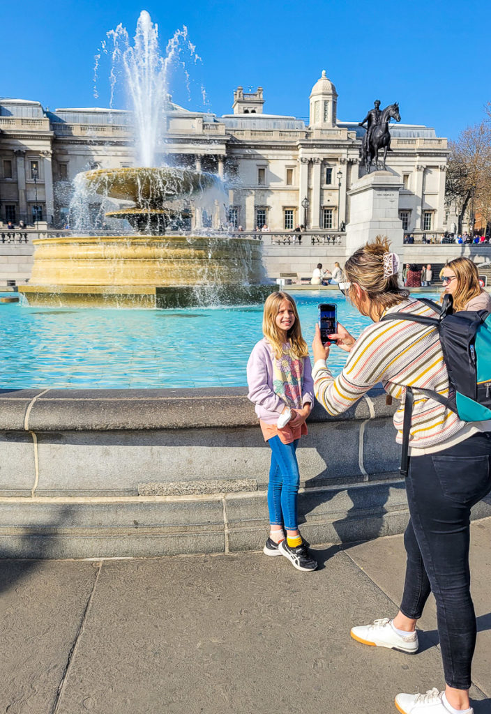 woman taking photo of child at Trafalgar Square, London