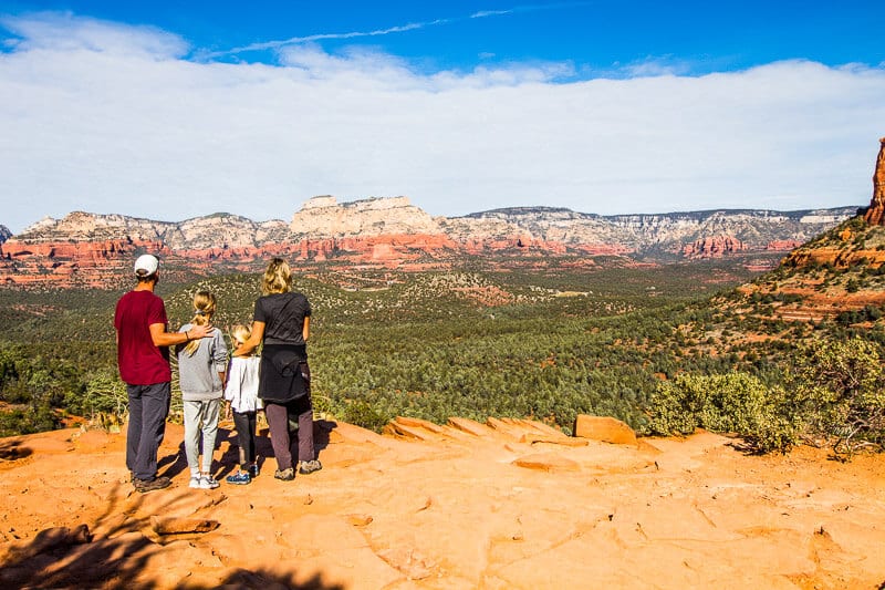 family standing on rock looking at sedona landscape