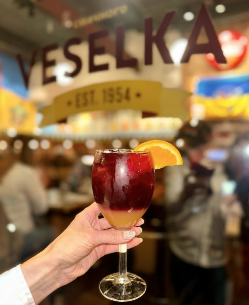 woman holding cocktail in front of veselka bar