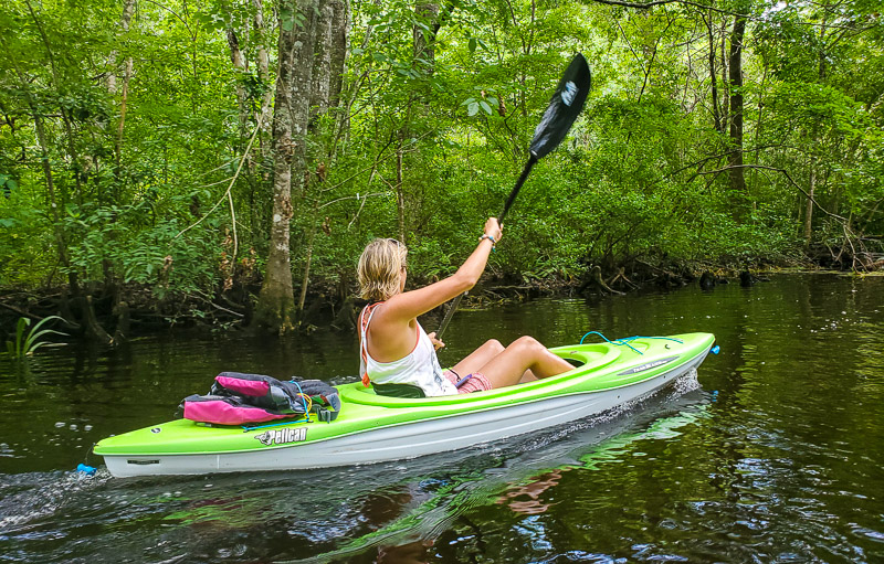 woman kayaking next to trees