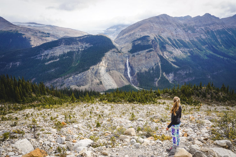 A person standing in front of a mountain, on a rocky path