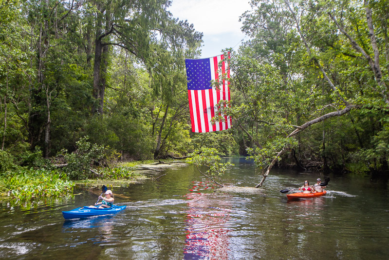 kayakers under american flag on Wacissa River, Florida