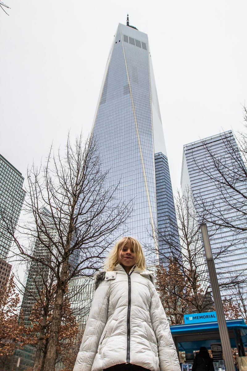 young girl standing In front of the One World Observatory at the World Trade Center in New York City.