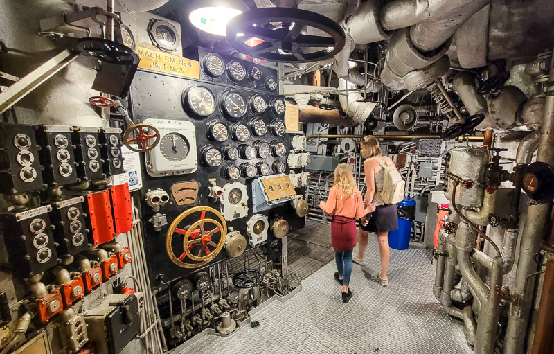 people standing inside battleship north carolina in front of controls