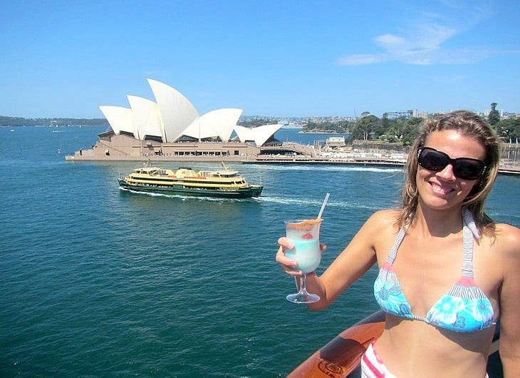 woman posing with cocktail on carnival spirit in sydney harbour with opera house views