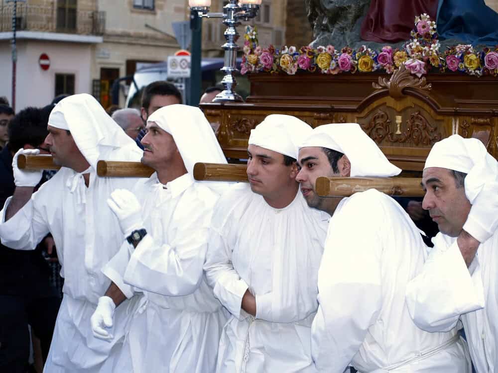 Easter in Malta men in white robes carrying a float