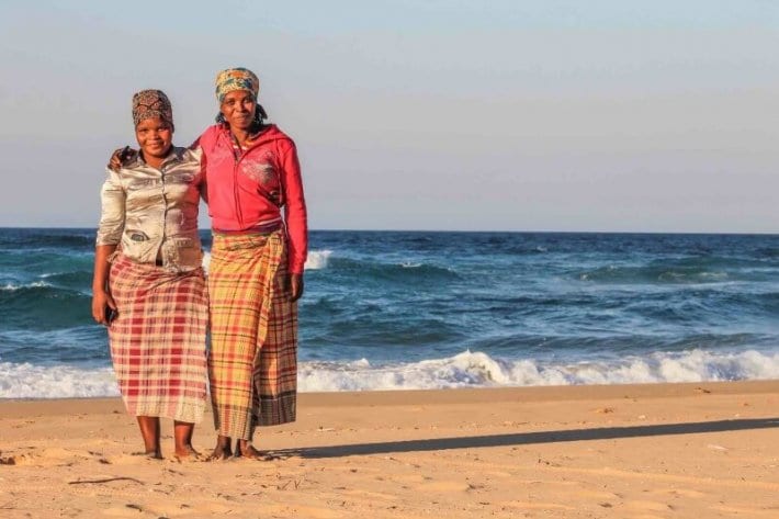 two Mozambique women hugging on sand