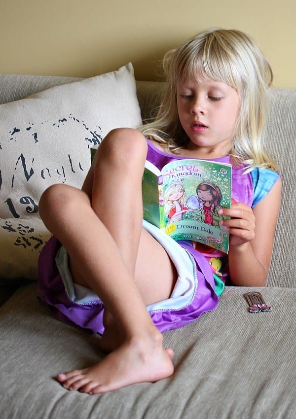 A little girl sitting on a couch reading a book