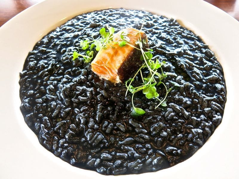 a bowl of Risotto with squid ink and salmon